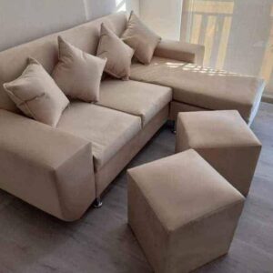 Sofá seccional color beige con cojines beige y dos puffs
